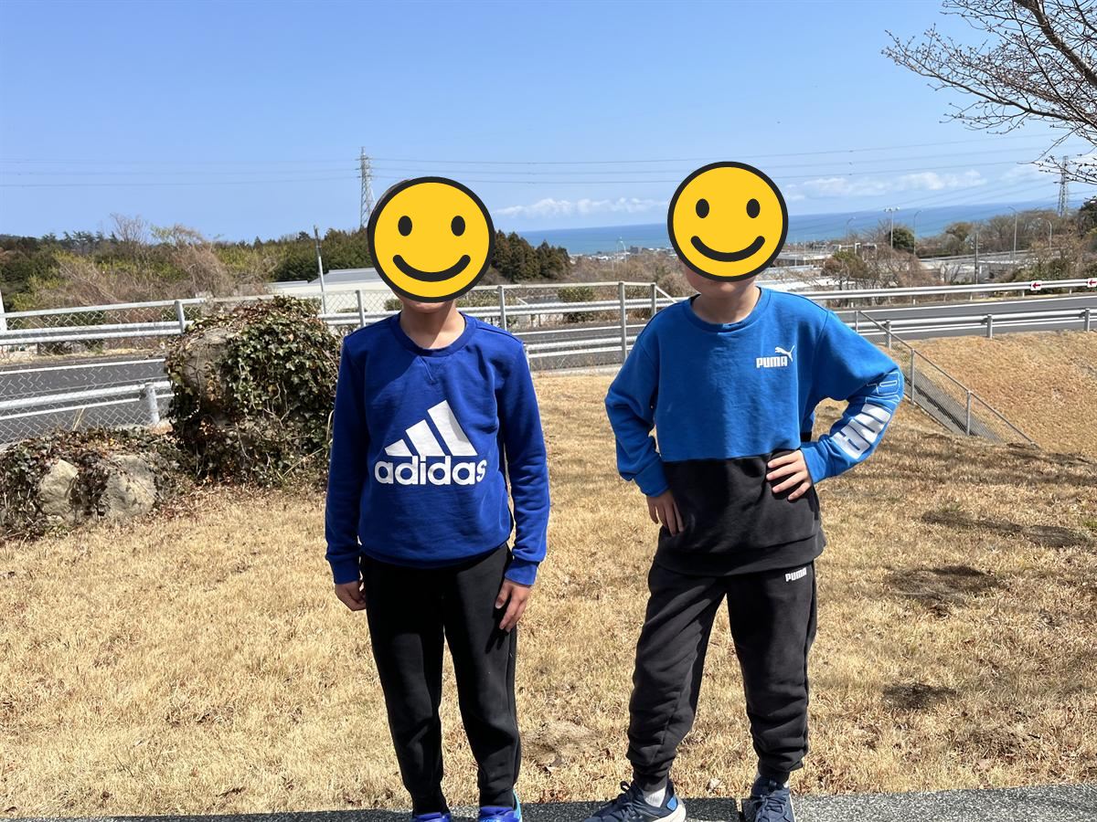 常磐道・日立中央パーキングエリアの丘の上から海を背にして立つ小学生2人