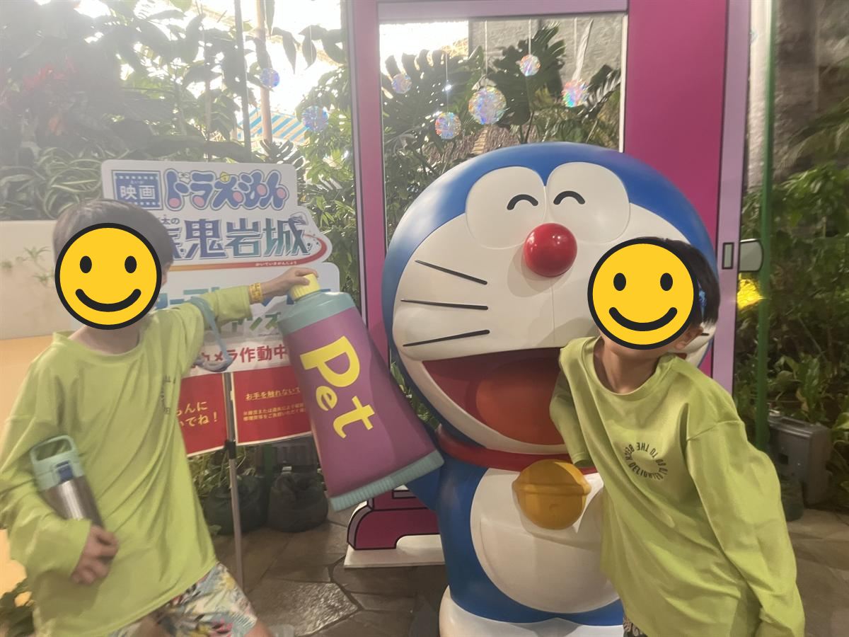 ハワイアンズ館内のドラえもん像と並んで写真を撮る小学生2人