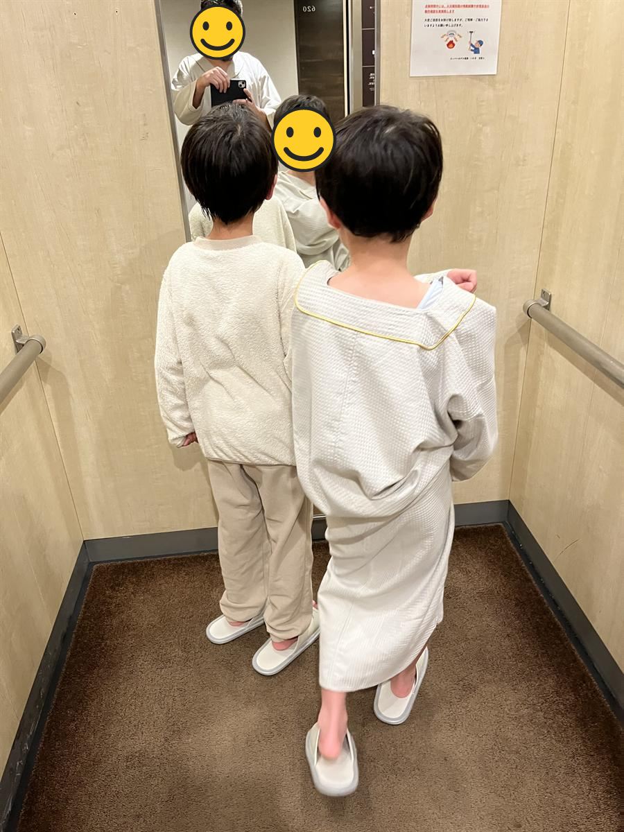 館内着とスリッパでホテルの大浴場へ向かう小学生2人