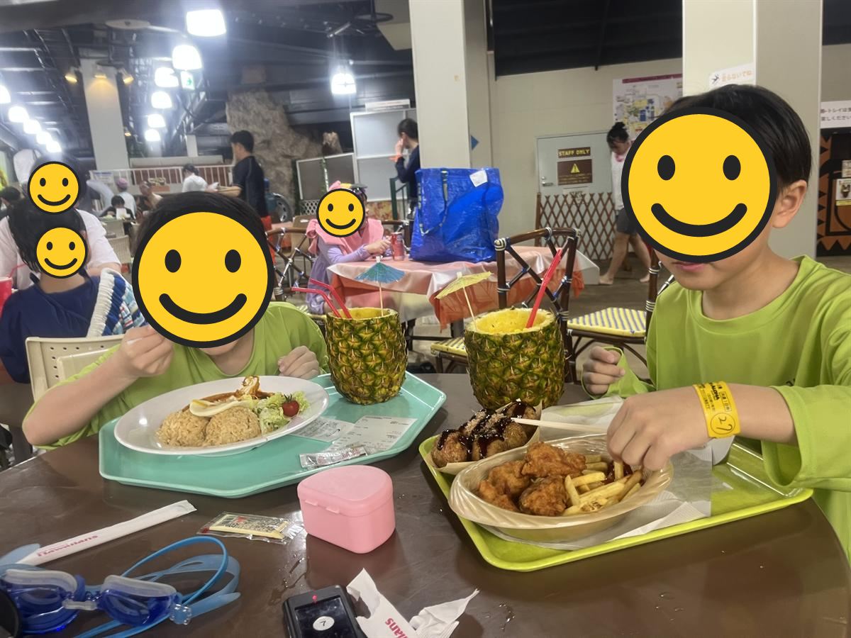 パイナップルを器にしたジュースとロコモコを前にする小学生2人