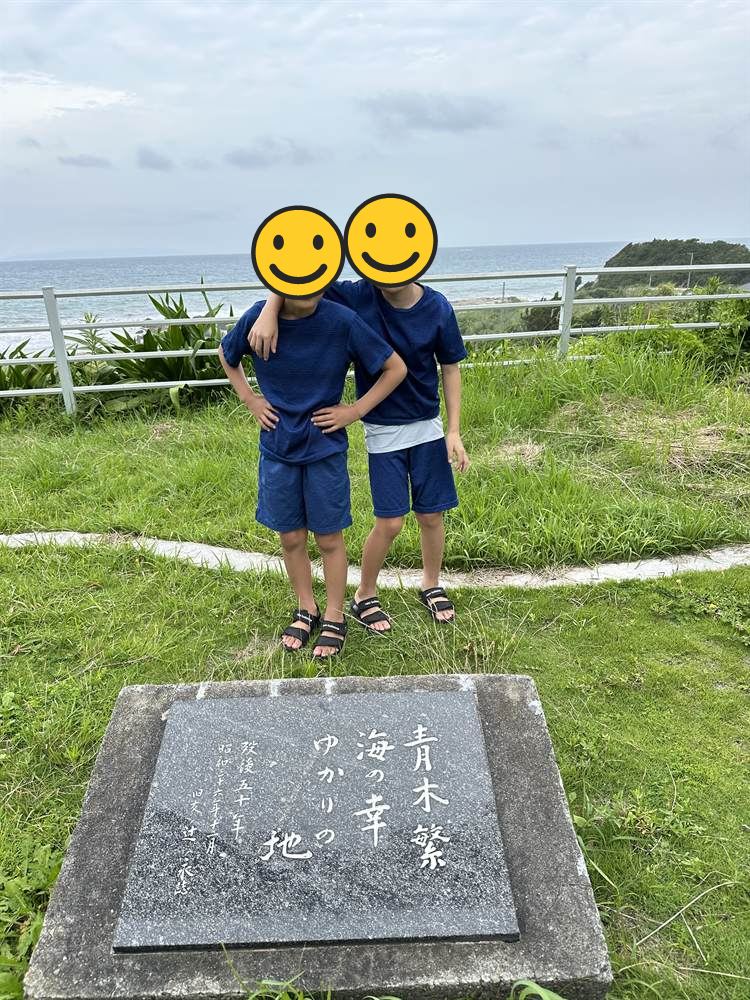 青木繁 海の幸 ゆかりの地と刻まれた石碑の前に立つ兄弟