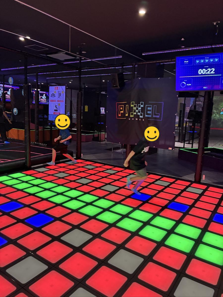 PIXELの光る床の上を走る子どもたち。床は赤と緑のパネルで埋まっている