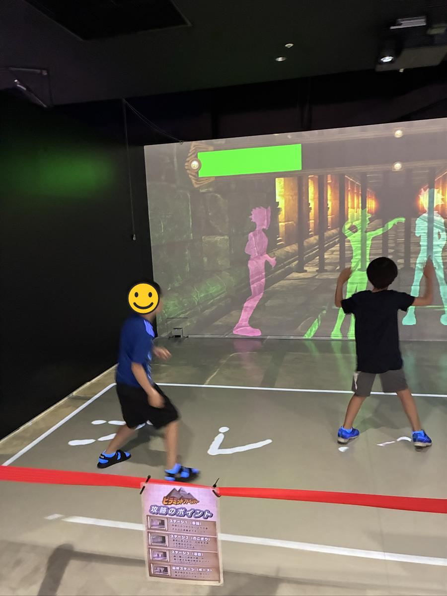 ピラミッドアドベンチャーで壁のプロジェクションに向かって体を動かす子どもたち