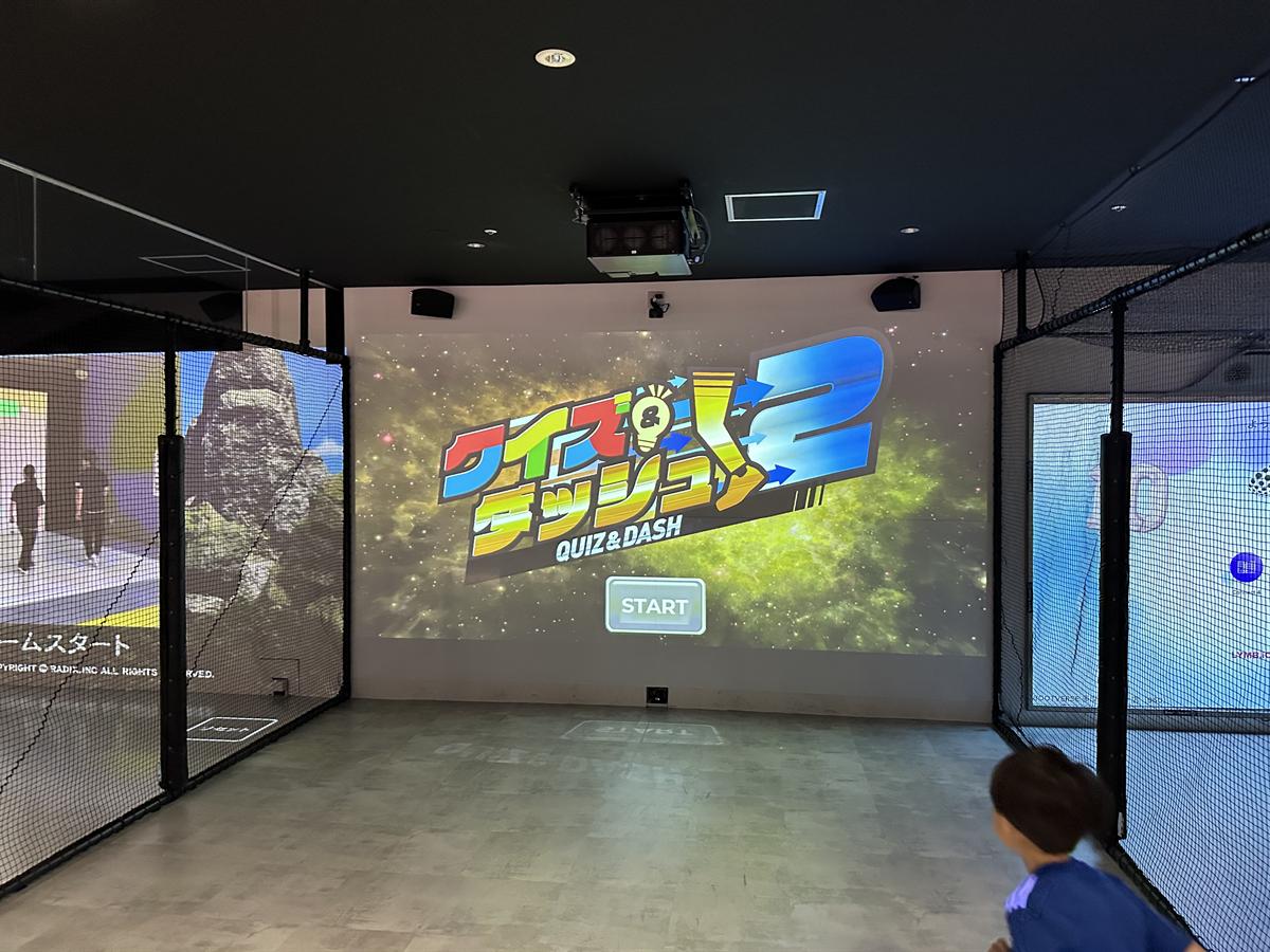 クイズ&ダッシュ2のスタート画面が投影された壁。左右にもゲーム用のスクリーンが並ぶ