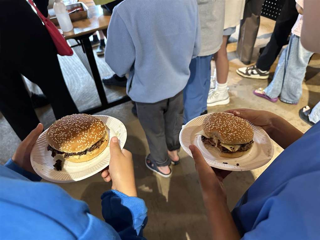 完成したハンバーガーを紙皿にのせて持つ子ども2人の手元