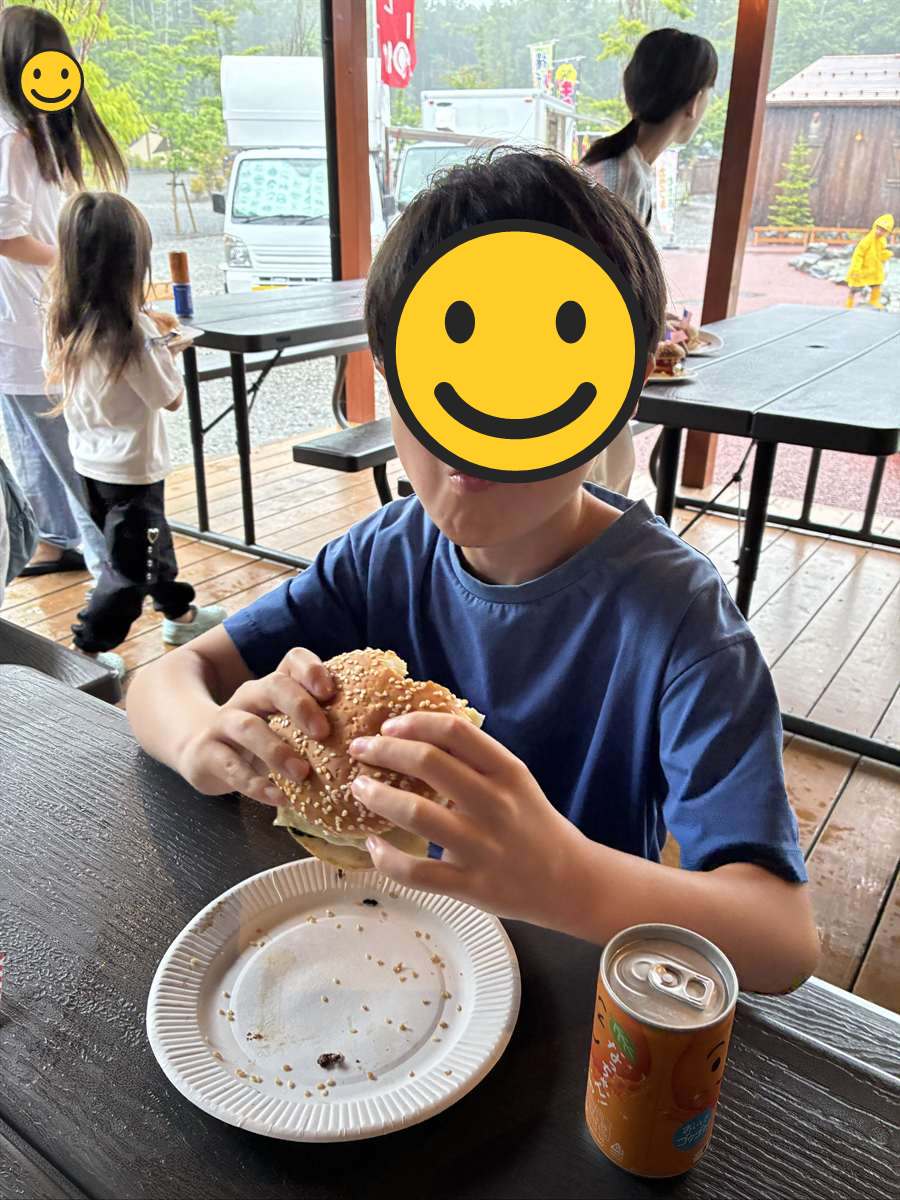 できあがったハンバーガーを両手で持ってかじる子ども