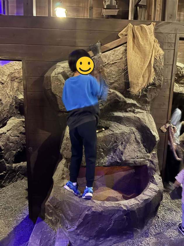 紫色に照らされた洞窟風の岩場を登る子ども