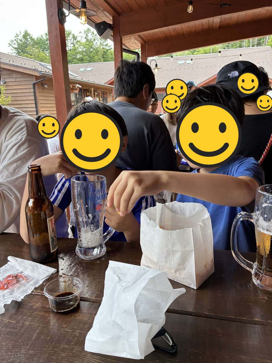 ジョッキに入った琥珀色の飲み物と茶色い瓶を前にした子ども2人