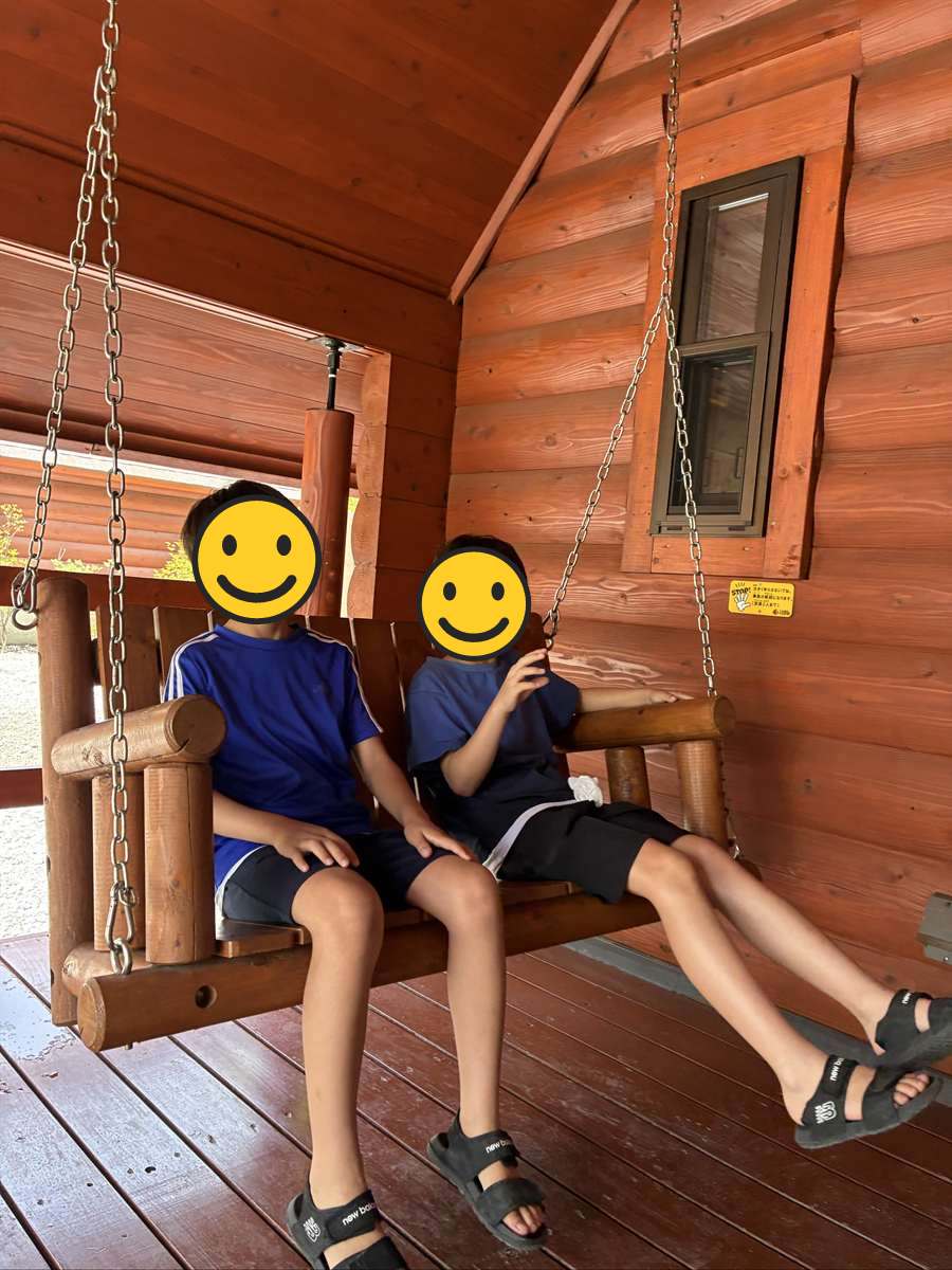 キャビンのブランコベンチに並んで座る子ども2人