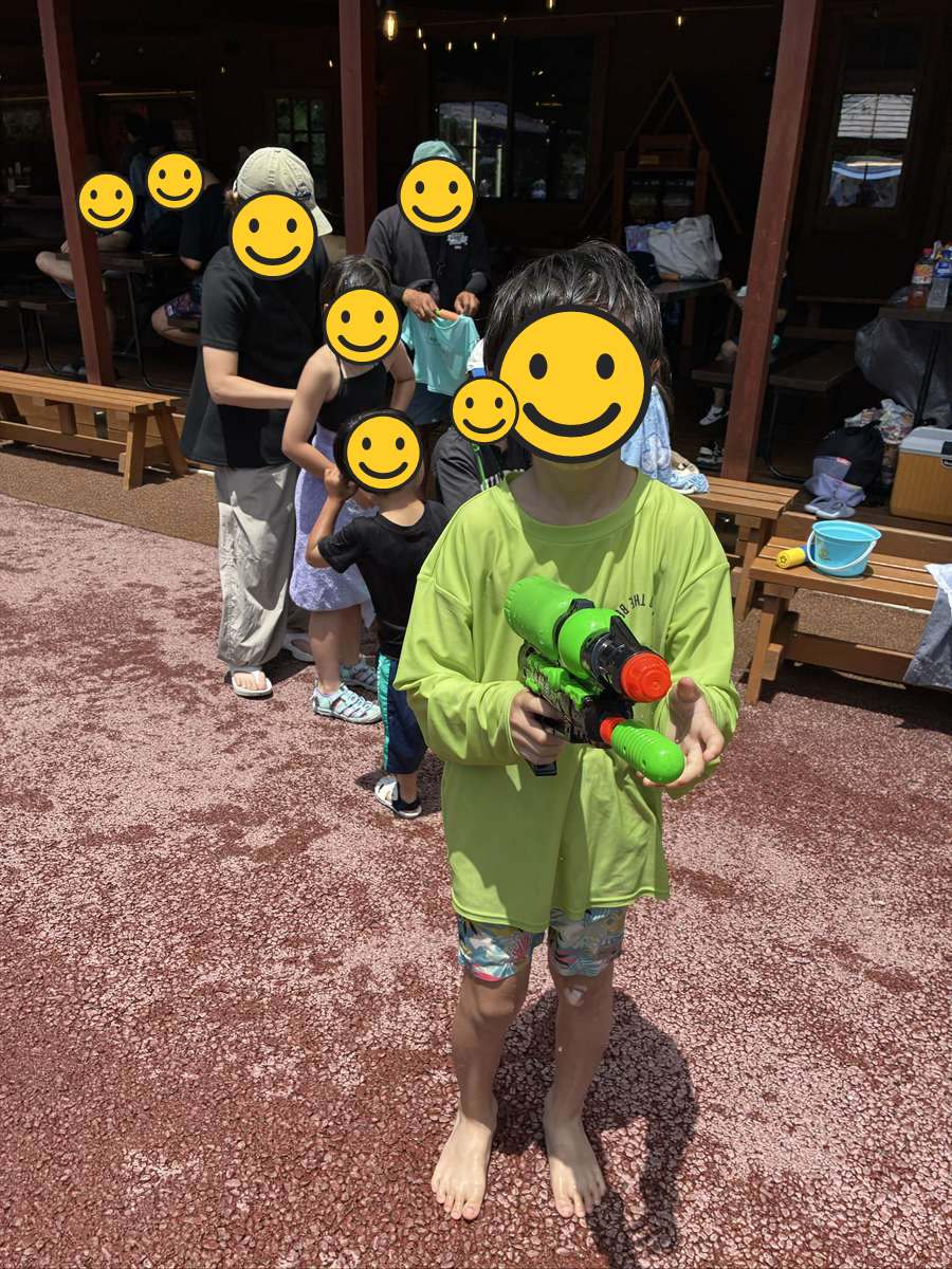 大きな水鉄砲を持ってポーズをとる、髪も服も濡れた子ども