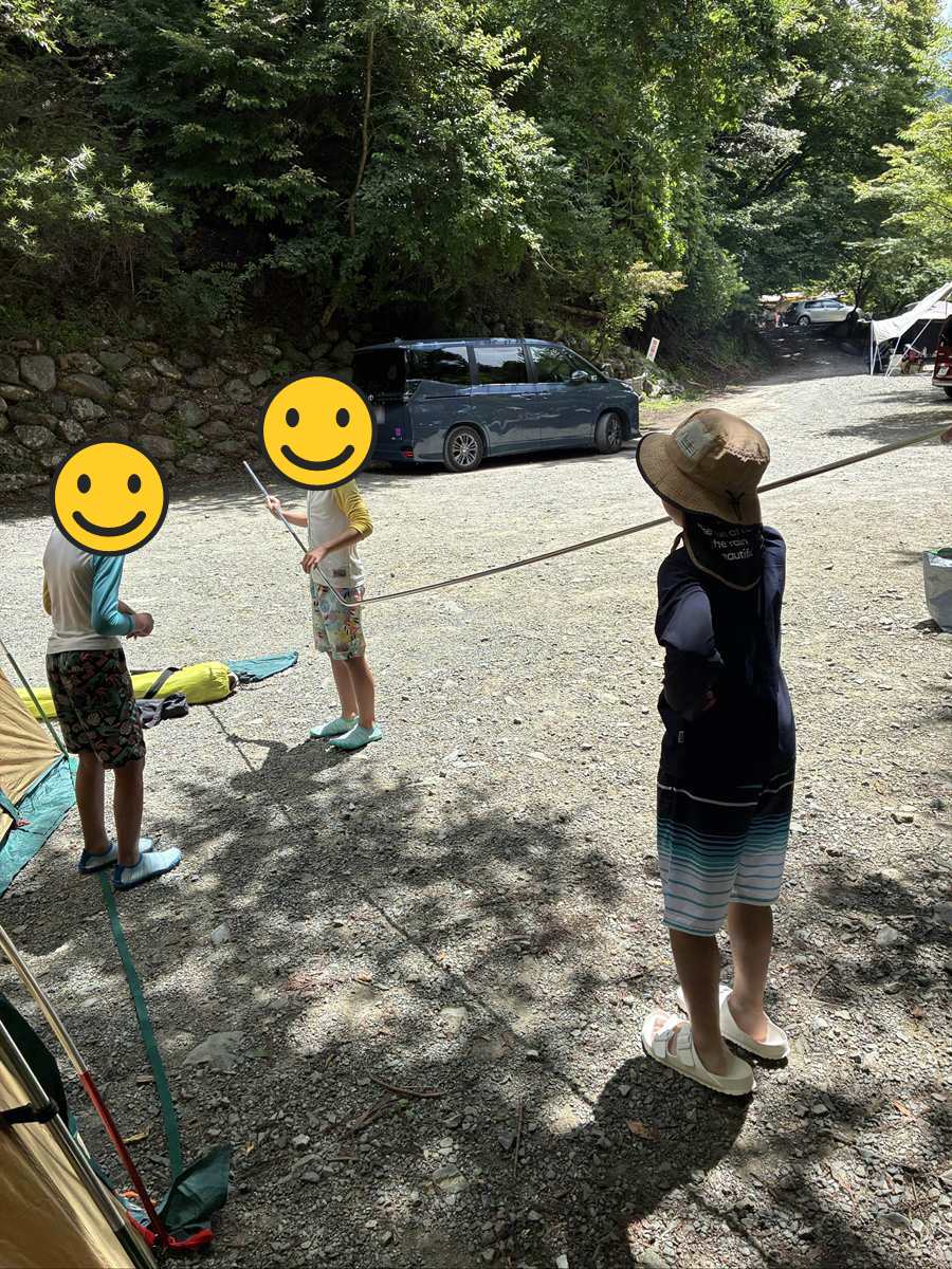 道志の森キャンプ場のサイト。砂利の地面にテントを張り、すぐ横に車を停めている
