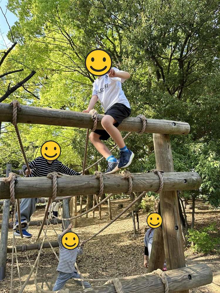 高い丸太の上に座ってピースサインをする子ども