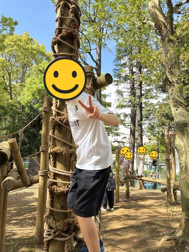 ロープが巻かれた丸太の前でポーズをとる子ども