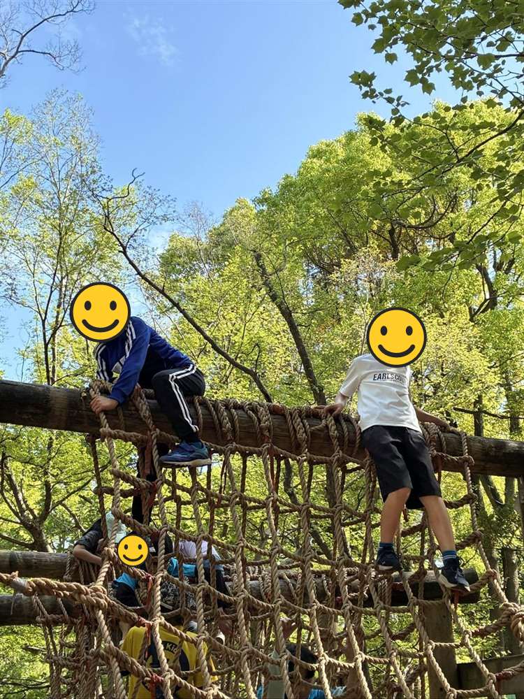 ロープの網の上に並んで座る子どもたち