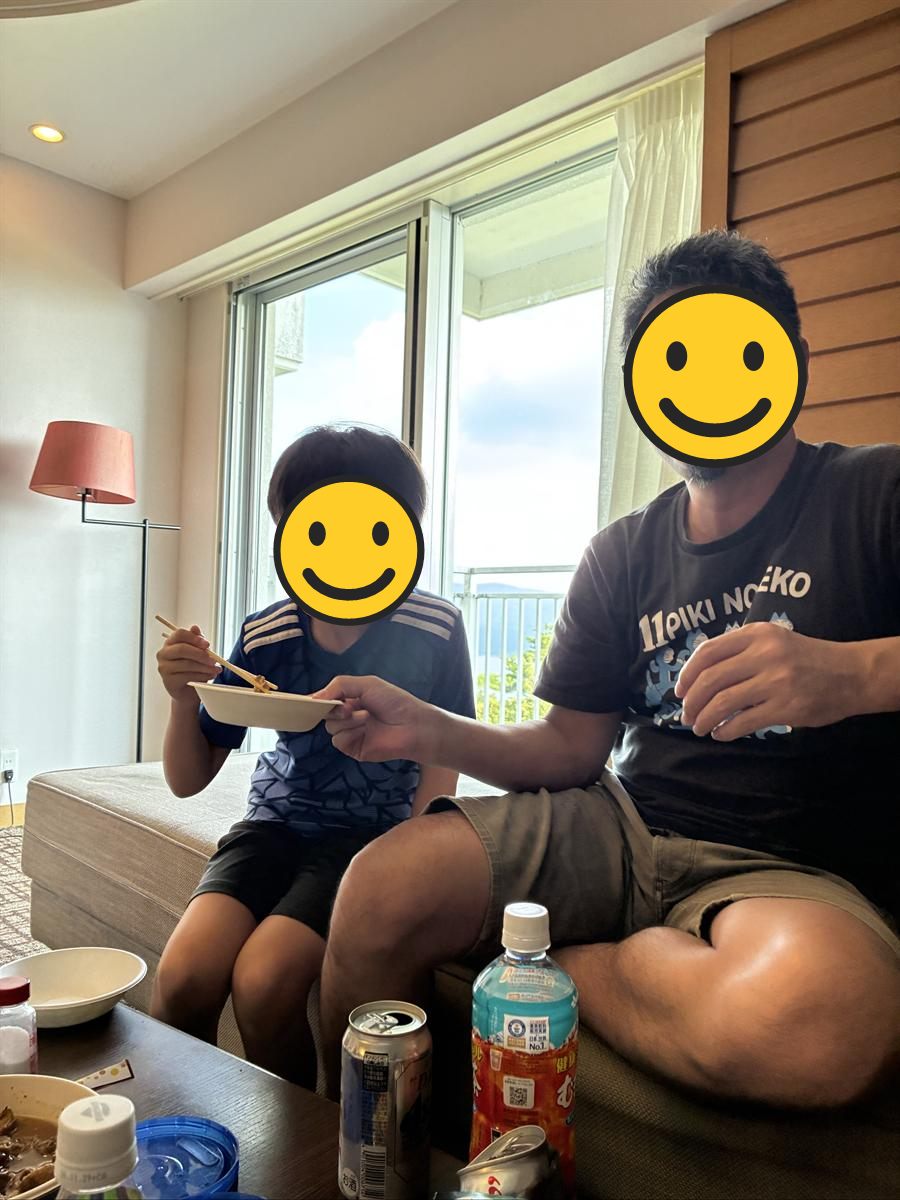 部屋のソファで小皿のつまみを食べる父と男の子
