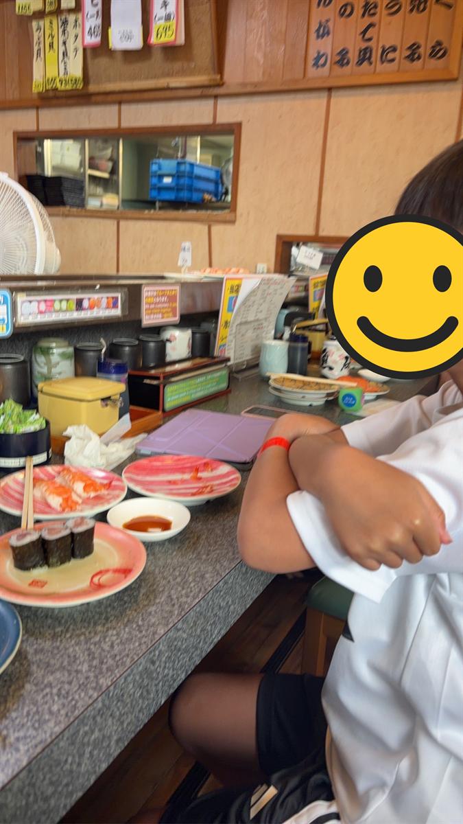 回転寿司のカウンターで皿を前にした男の子の横顔