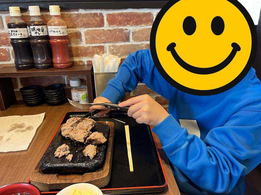 熱した石のプレートにのったハンバーグを、子どもがナイフで切り分けている