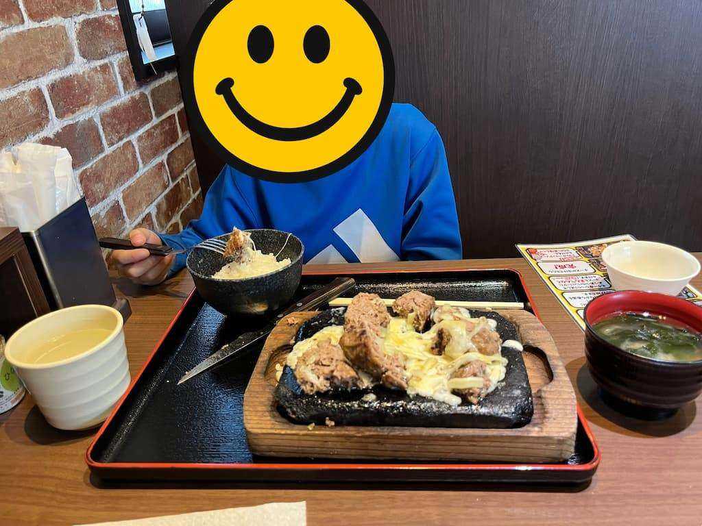 チーズがかかったハンバーグの鉄板と、ごはん・味噌汁・空の茶碗が並んだトレー