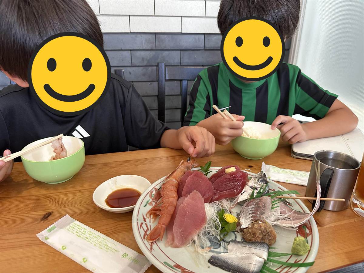 カネシチ水産の刺身の盛り合わせとごはん茶碗を持つ子ども2人