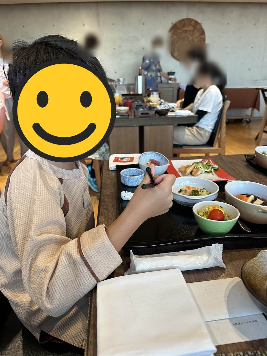 館内着のまま夕食の小鉢を食べる次男