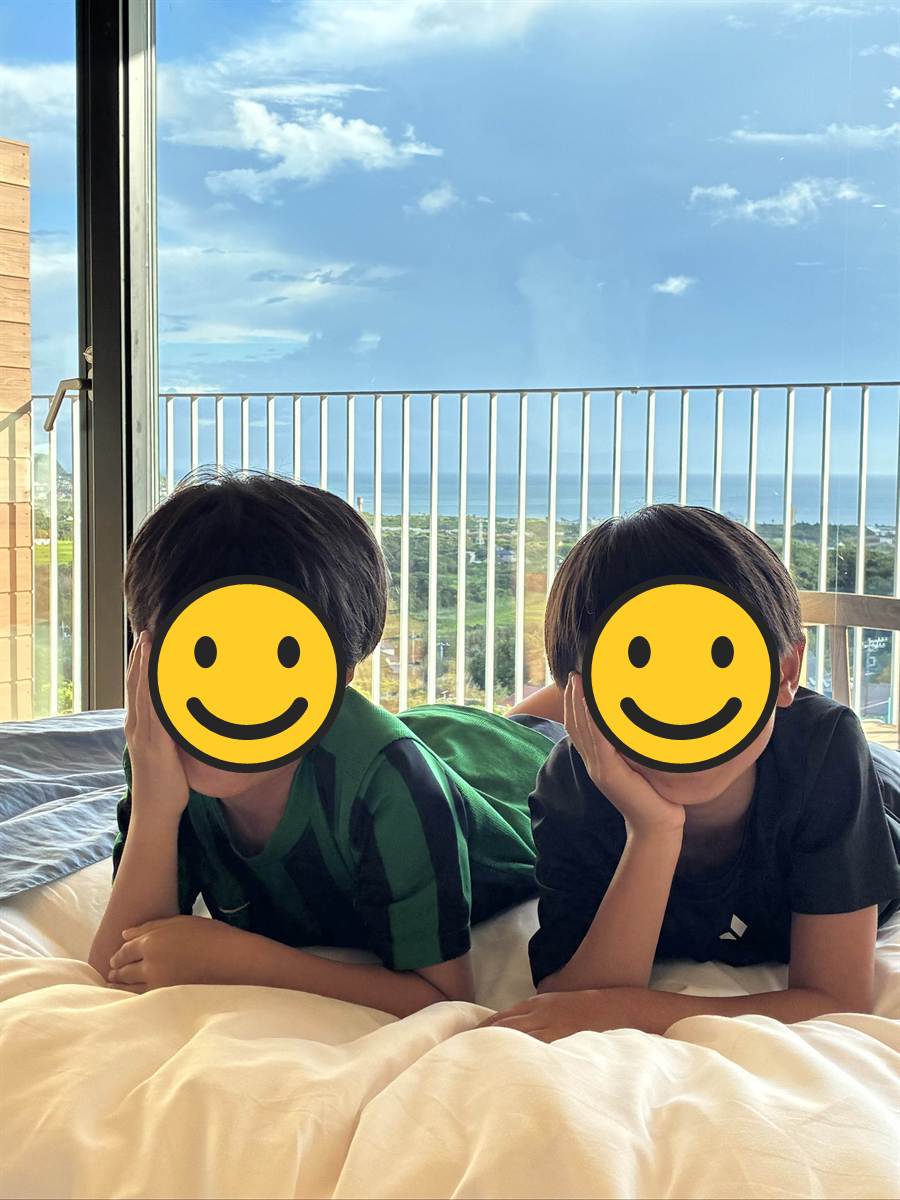 ベッドに並んでうつ伏せになり頬づえをつく子ども2人