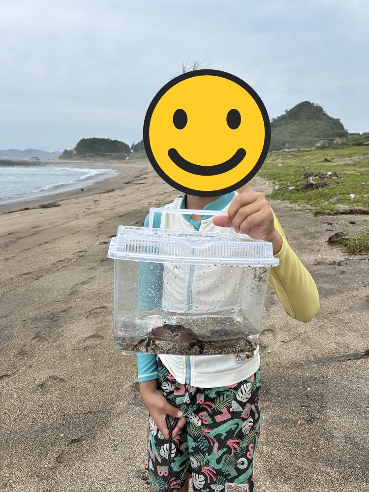 海エリアの砂浜でカニの入った虫かごを掲げるこども