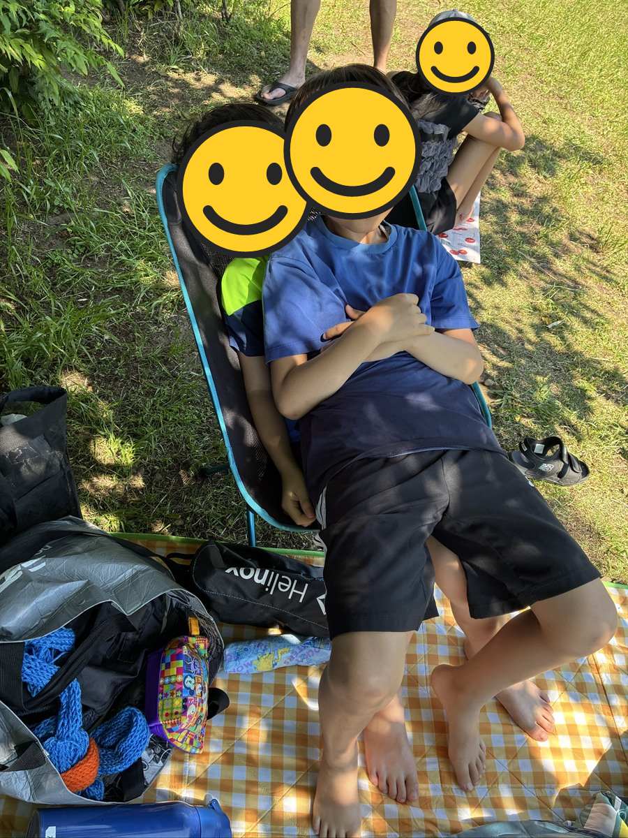 アウトドアチェア1脚に重なるように座って脱力する子ども2人