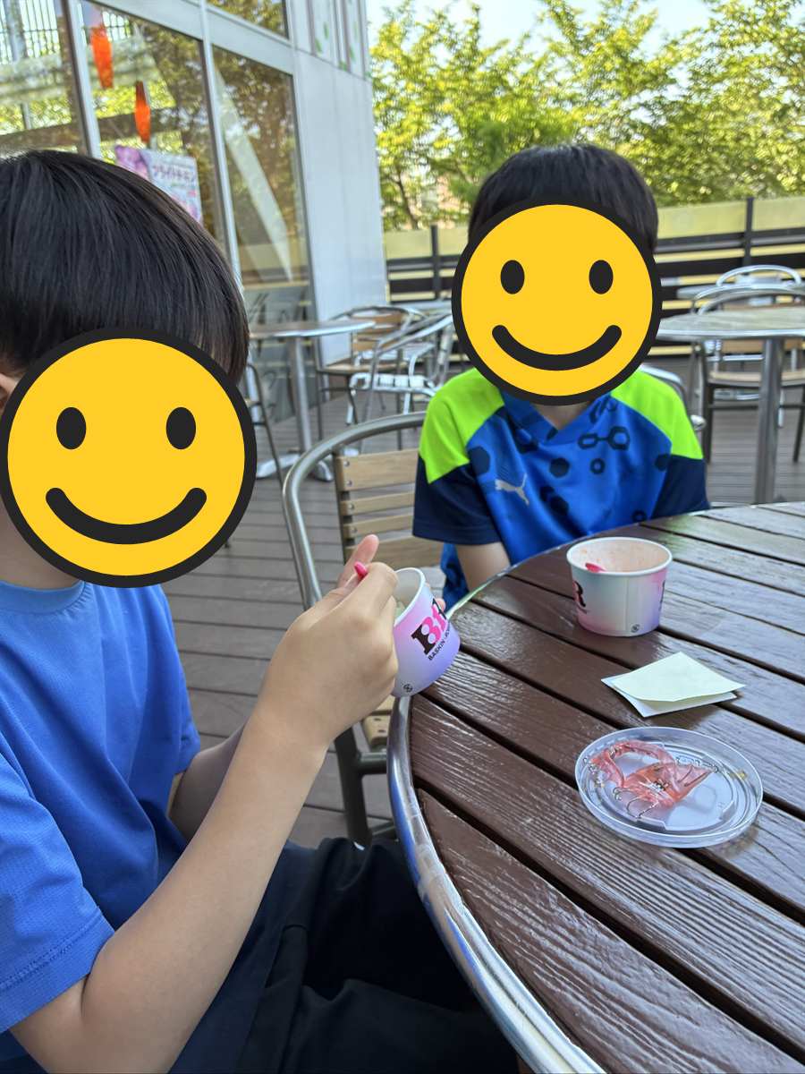 屋外テラス席でカップアイスを食べる子ども2人