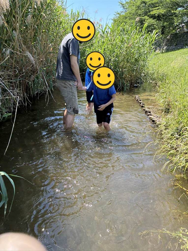 三沢川親水公園の浅い川に入って遊ぶ子どもと大人