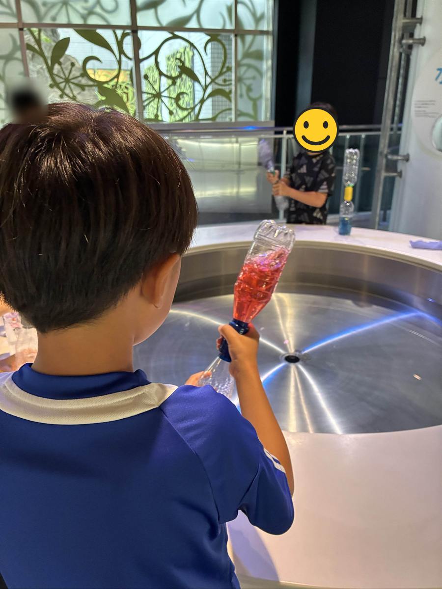 つないだペットボトルを傾けて中の水に渦をつくる子ども