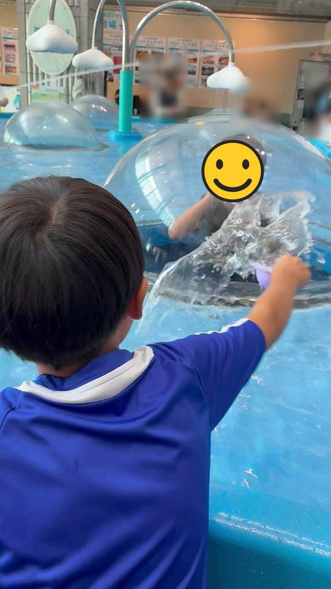 透明なドームの中にいる長男に外から水をかける次男