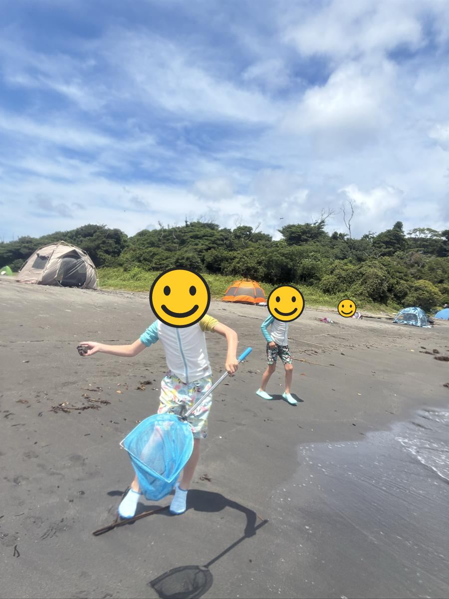 沖ノ島海水浴場の砂浜を網を持って走るこどもたち