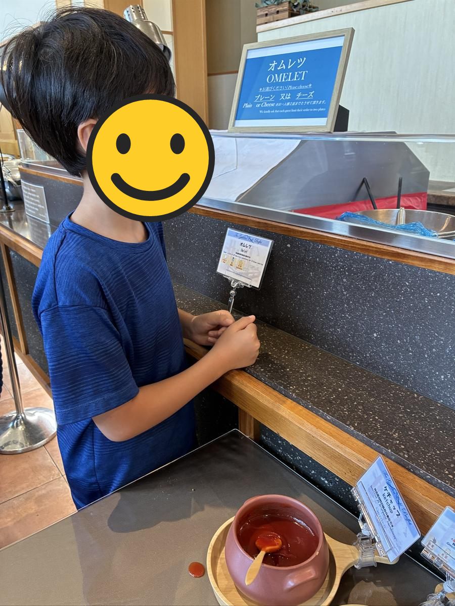 朝食ブッフェのオムレツコーナーの案内板を見る男の子