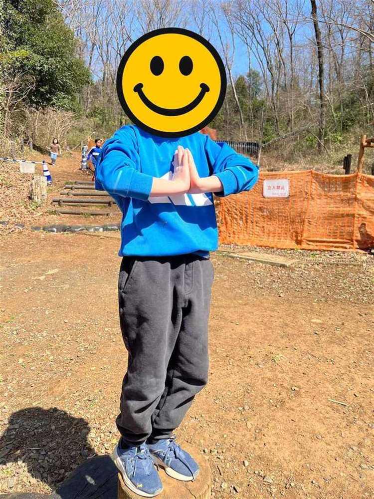 切り株の上に立ち、両手を合わせてポーズをとる子ども