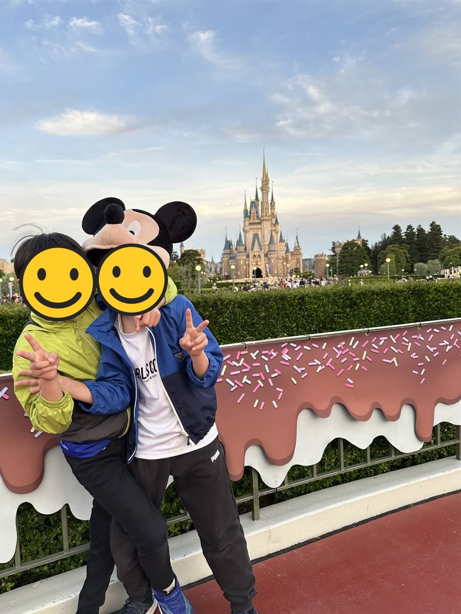 夕暮れのお城を背景にポーズをとる子ども2人