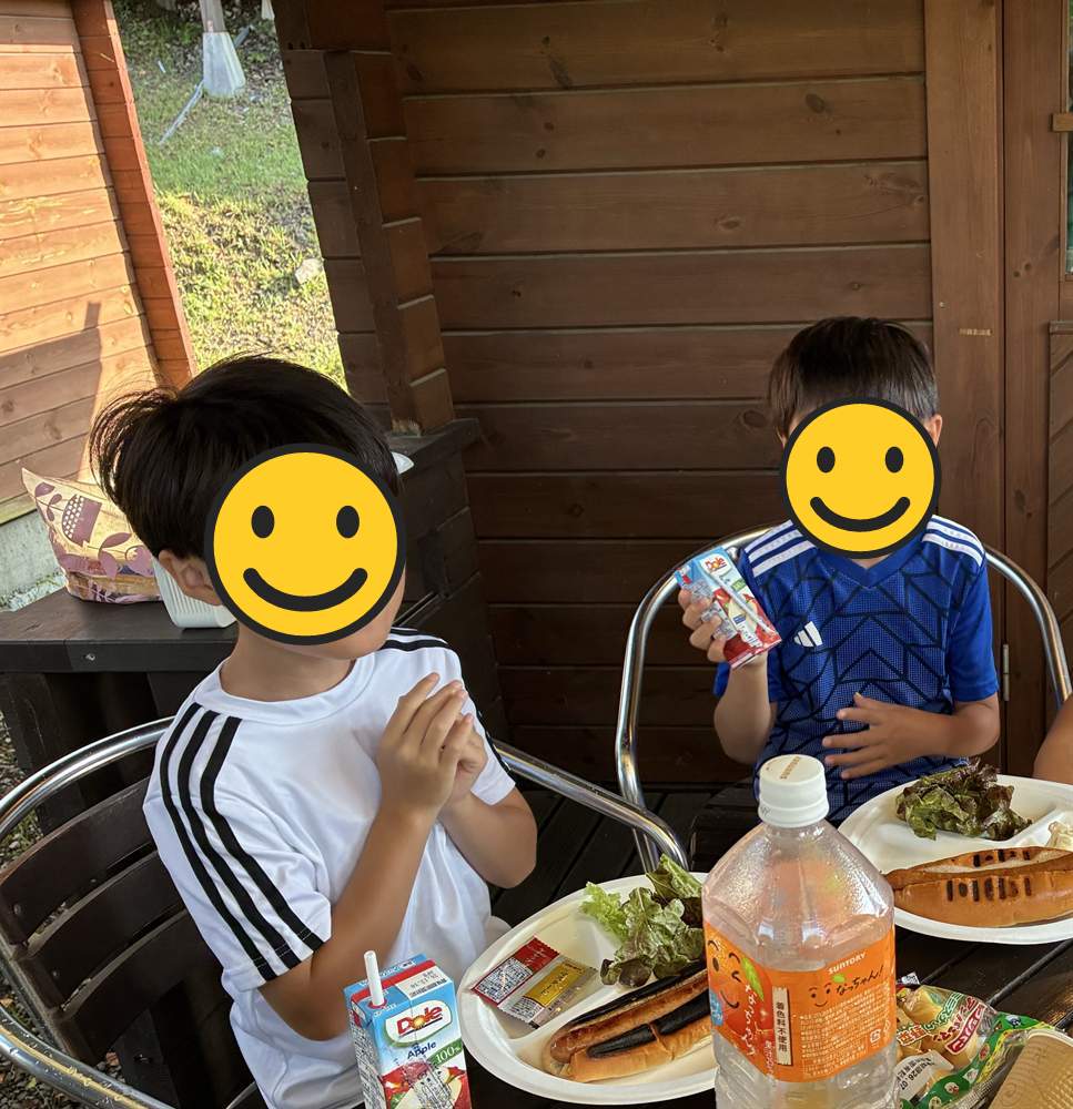 コテージのテラスでホットドッグの朝ごはんを食べる兄弟