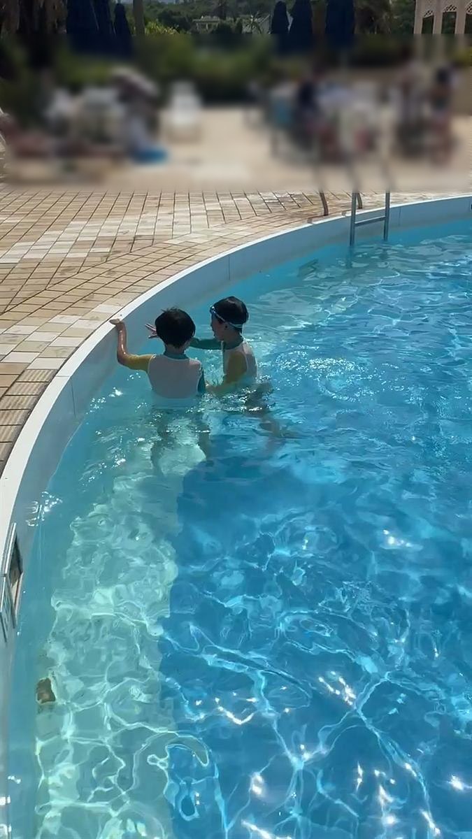 プールの縁につかまって並ぶ兄弟の後ろ姿