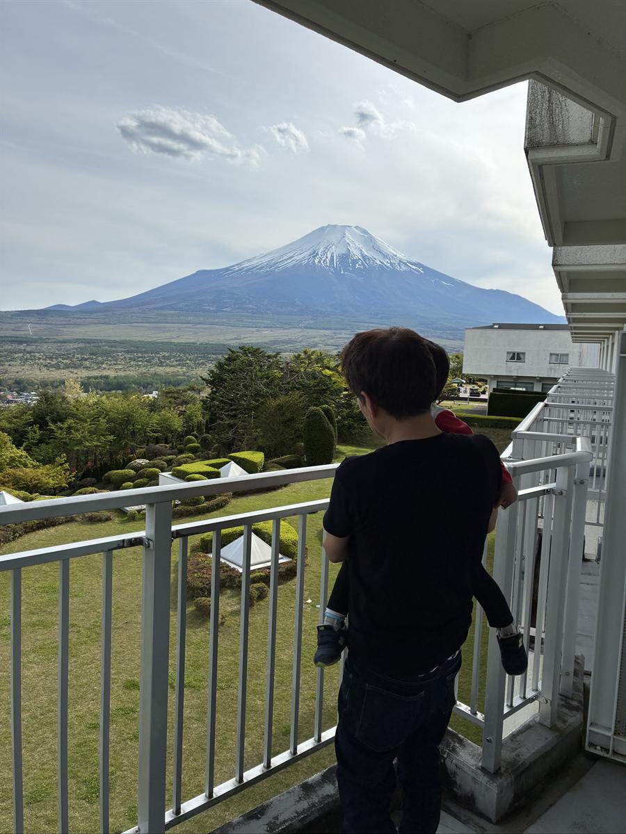 ホテルの通路から見える雪をかぶった富士山と、子どもを抱いて眺める大人
