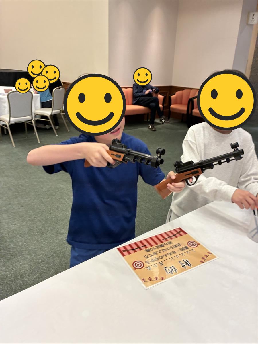 ホテルのイベントで射的のおもちゃの銃を構える子どもたち