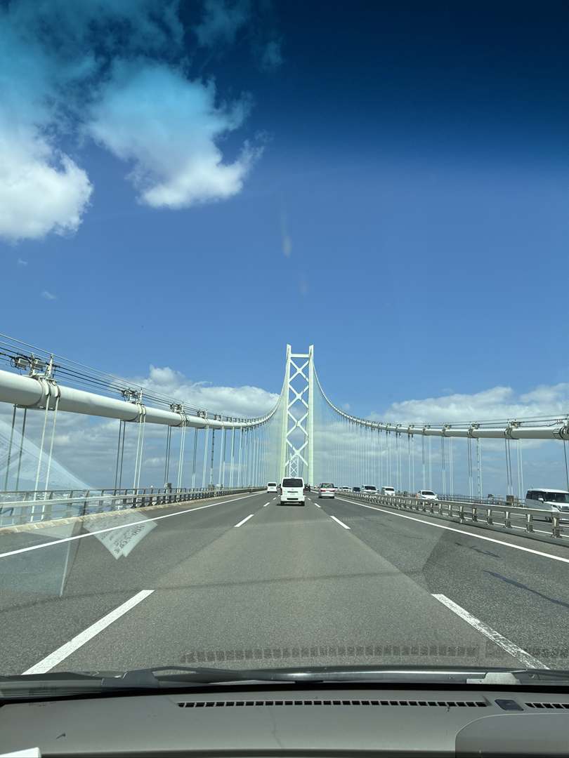 車の中から見た、明石海峡大橋の白い主塔と青空
