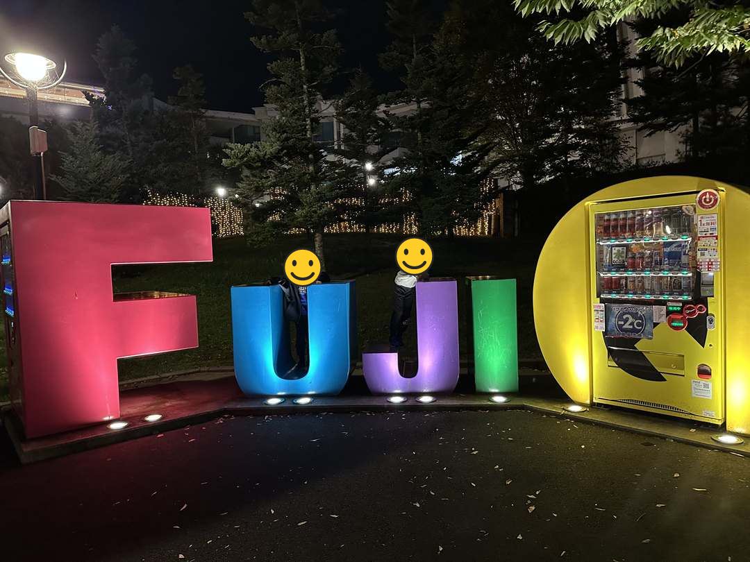 夜にライトアップされたFUJIQの大きな文字のオブジェと兄弟