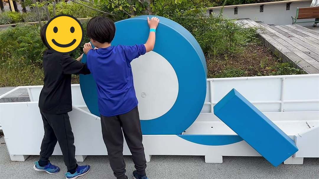 富士急ハイランドの大きな青いQの文字のオブジェを、兄弟で押して転がしている