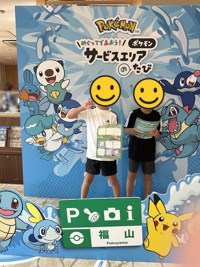 山陽道の福山SAで、ポケモンのサービスエリアのたびのパネルの前でスタンプ台紙を持つ兄弟