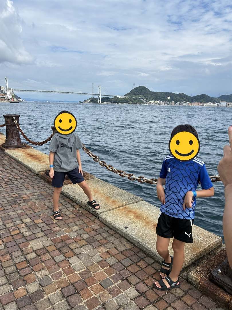 関門海峡の岸壁で関門橋をバックに立つ兄弟