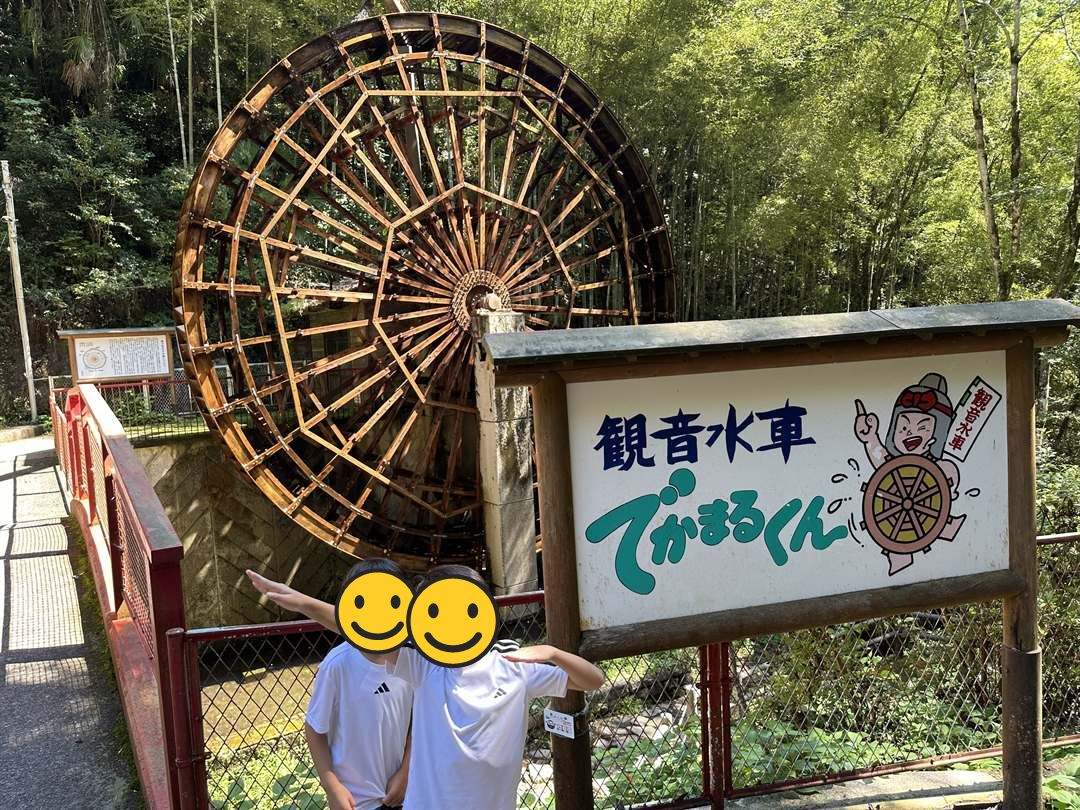 竹林の中に立つ大きな木の水車、観音水車でかまるくんの前の兄弟