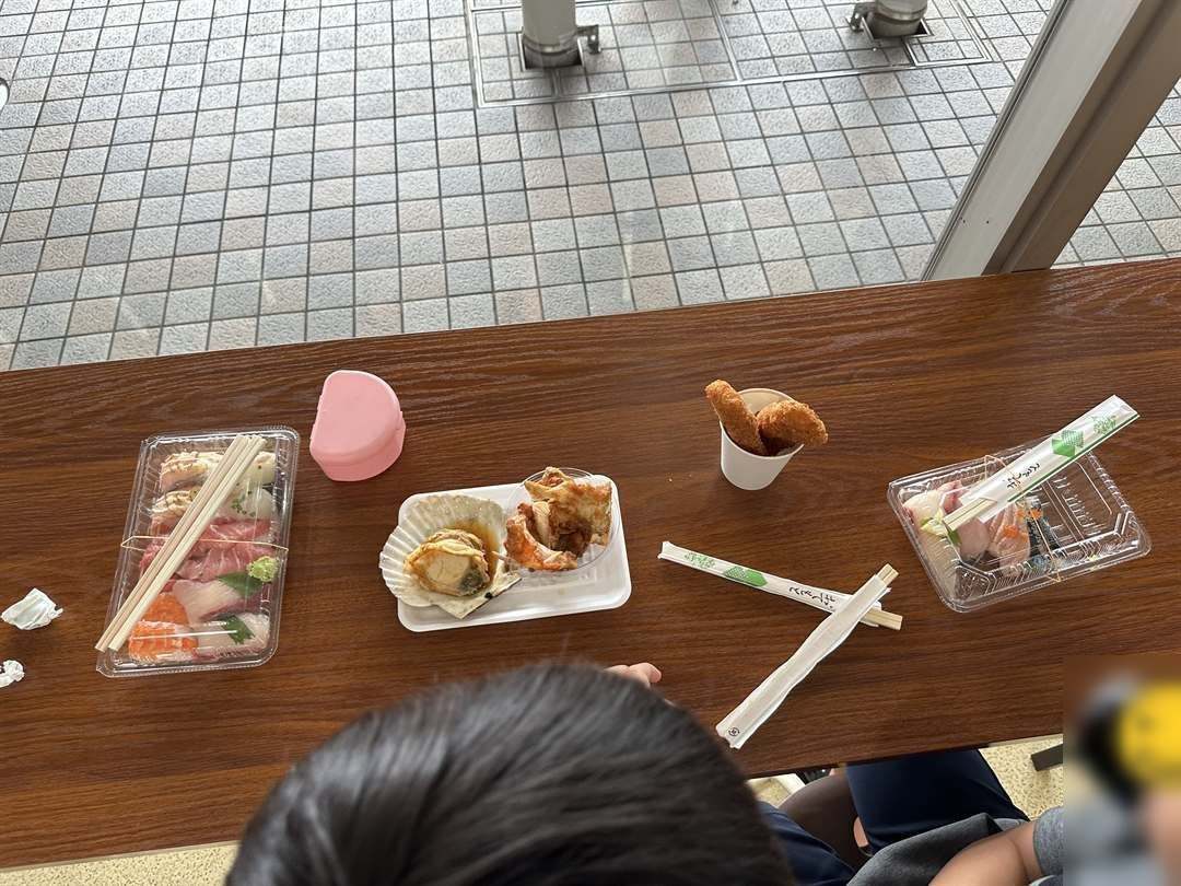 唐戸市場で買ったお寿司、焼きほたて、揚げ物を屋根の下のテーブルに並べた様子