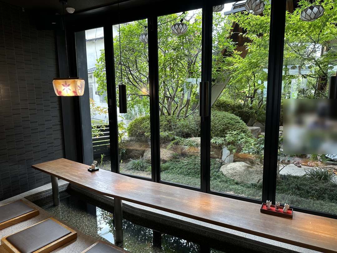 狐の足あとのカフェの中の足湯、窓辺の湯。大きな窓の向こうに庭