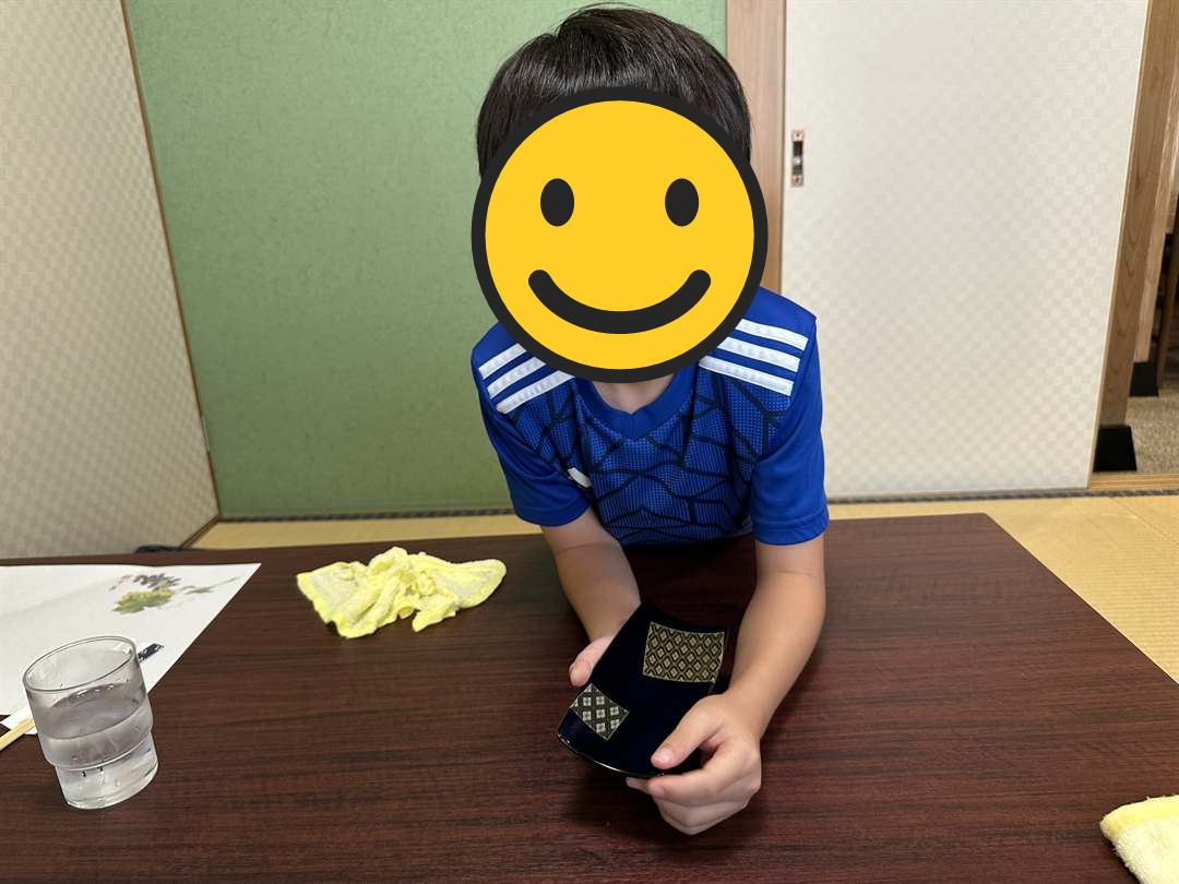 三ヶ日の炭焼うなぎ加茂の座敷で、うな重のふたを持つこども