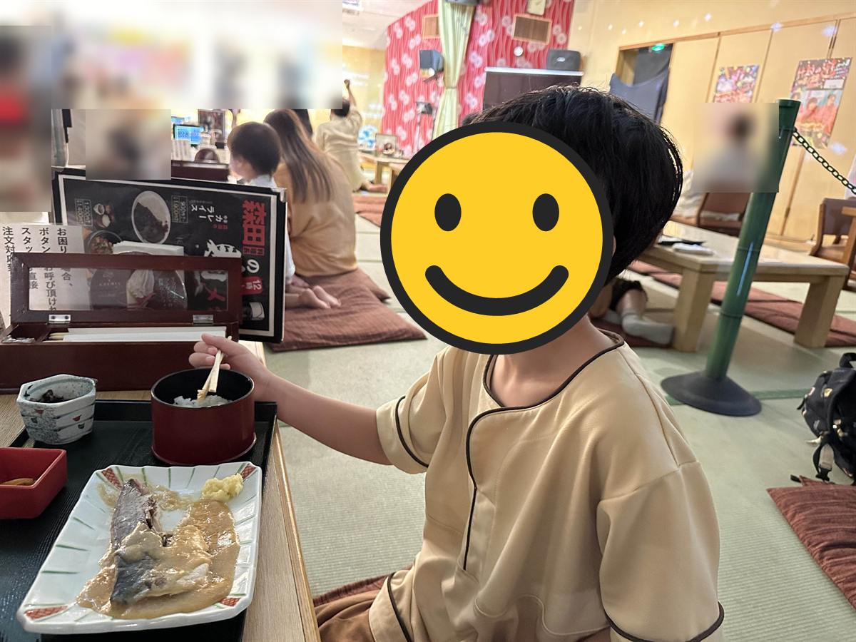 竹取の湯の畳の大広間で定食を食べる館内着の子ども
