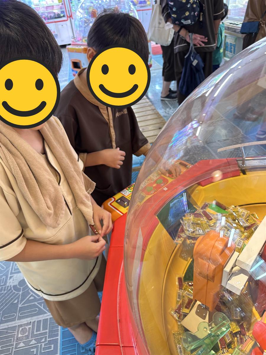 お菓子が入ったドーム型のゲーム機をのぞきこむ館内着の子ども2人